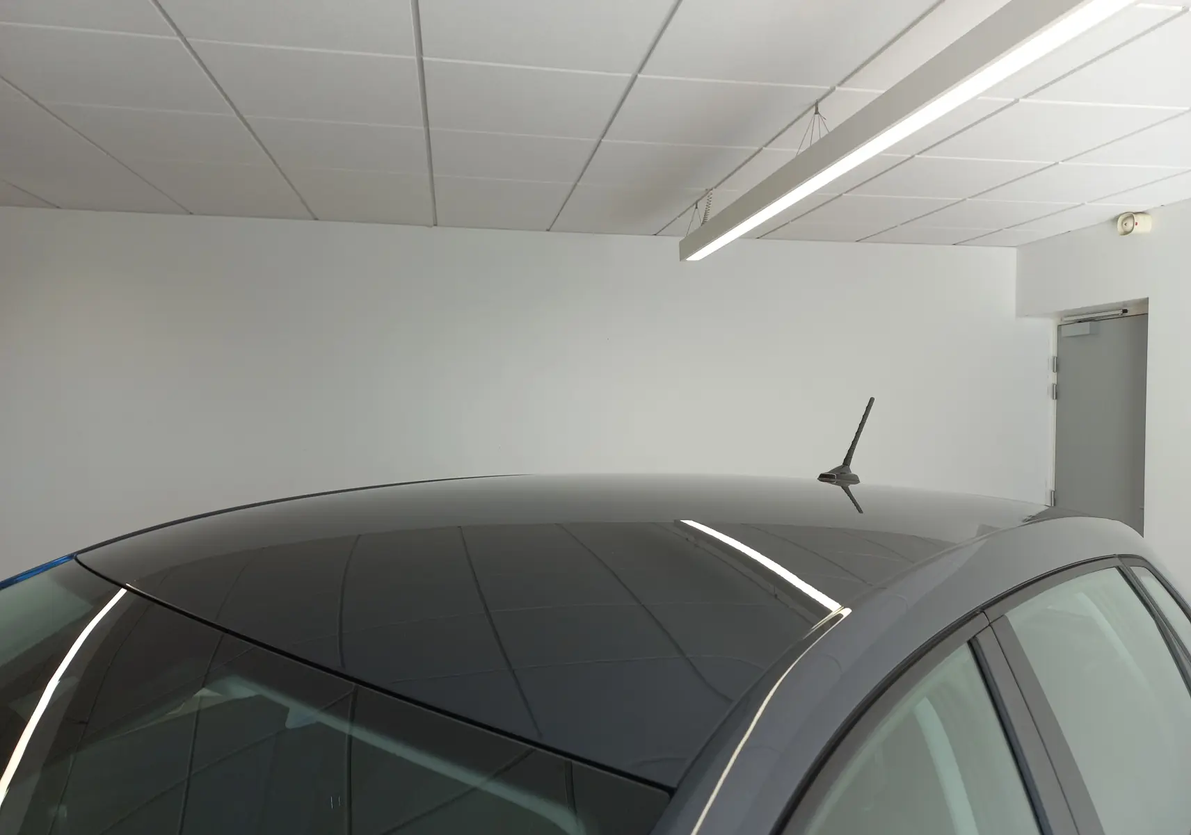 Toit panoramique noir brillant du SEAT Ibiza gris magnétique, vu en léger angle depuis l'arrière droit dans un intérieur blanc.