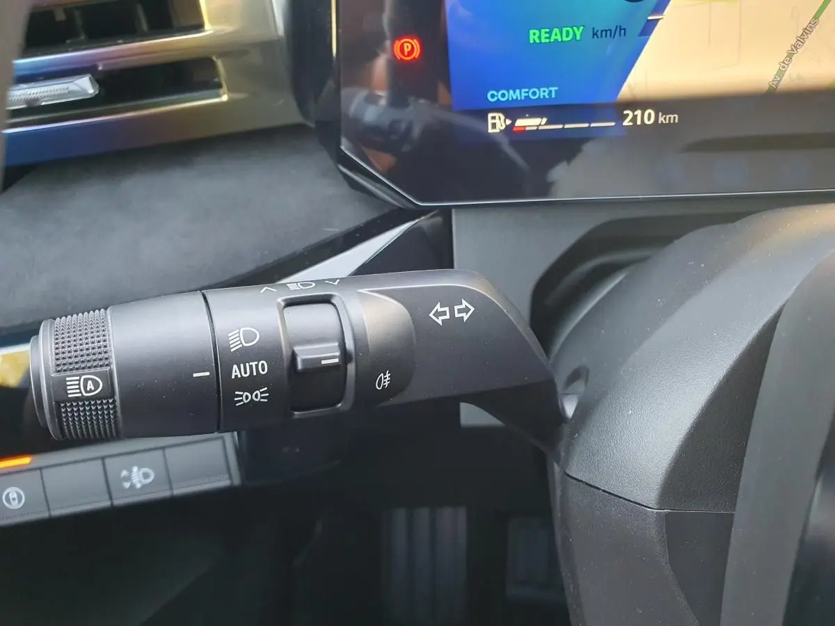 Gros plan sur la commande des feux et clignotants à gauche du volant dans l'habitacle de la Renault Clio VI hybride.