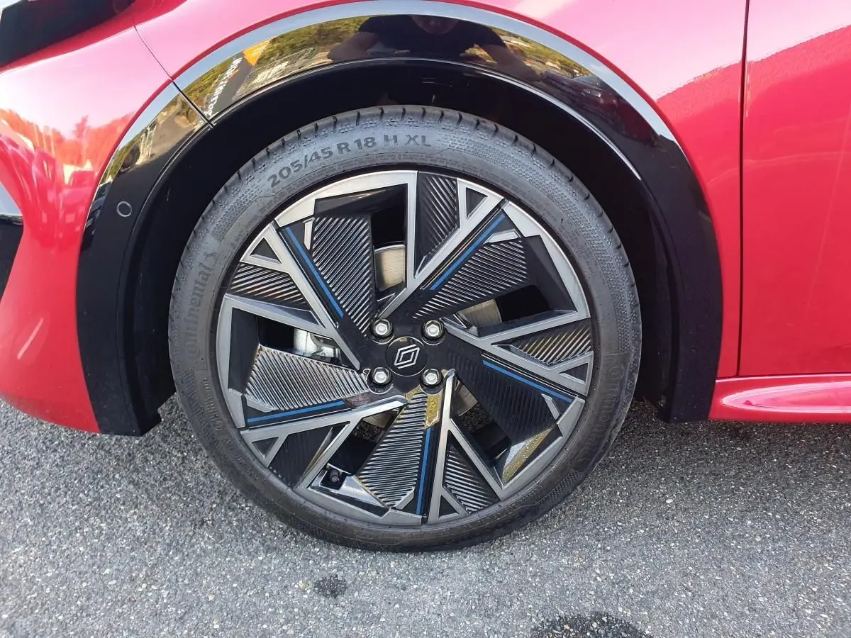 Gros plan sur la jante alliage diamantée 18” cosmic noire et grise du côté avant gauche d’une Renault Clio VI rouge absolu.