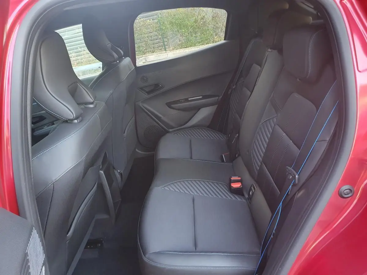 Vue intérieure côté droit des sièges arrière en tissu noir avec surpiqûres bleues d'une Renault Clio VI rouge absolu.
