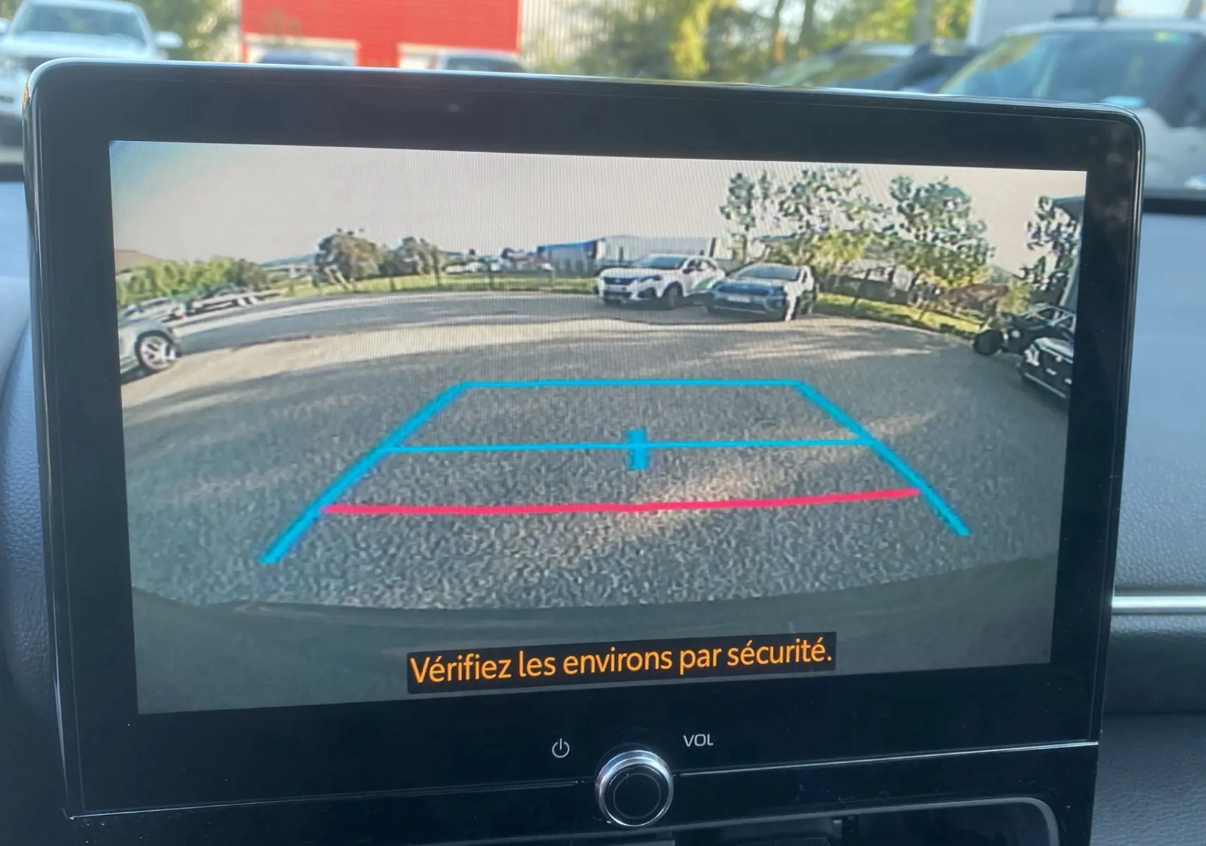 Vue de l'écran de la caméra de recul d'une Toyota Yaris Cross gris atlas, affichant les lignes de guidage au parking.