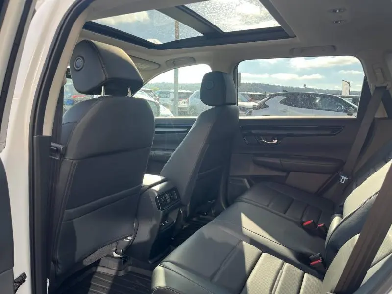 Vue intérieure arrière du Honda CR-V 2024 avec sièges en cuir noir et toit panoramique en verre ouvert.