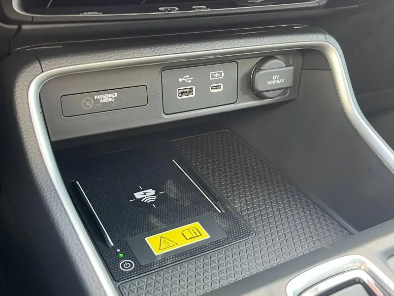 Vue rapprochée de la console centrale noire du Honda CR-V 2024 avec ports USB, prise 12V et zone de recharge sans fil.