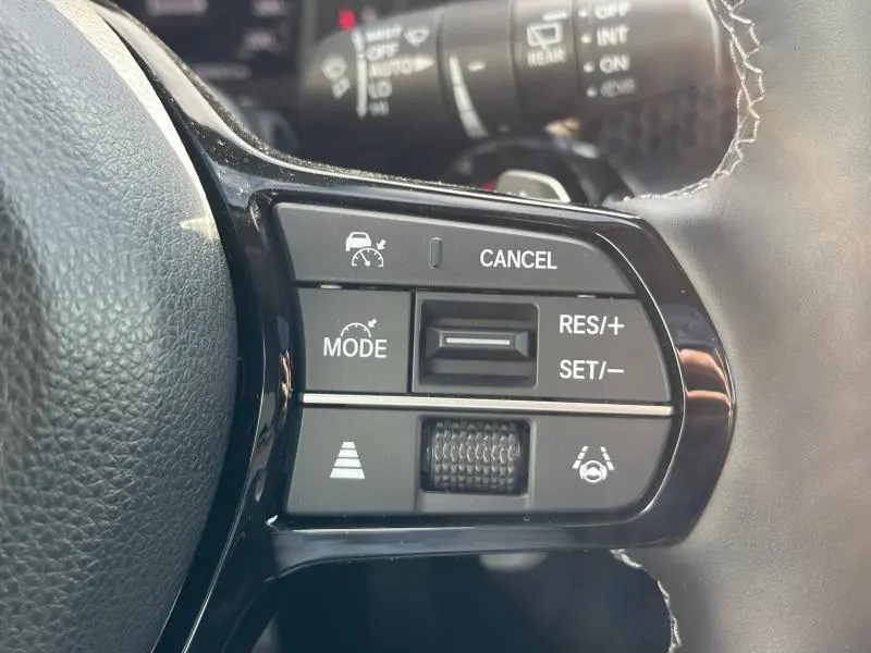 Gros plan sur les commandes noires du volant cuir du Honda CR-V 2024, avec boutons de régulateur de vitesse et assistance à la conduite.