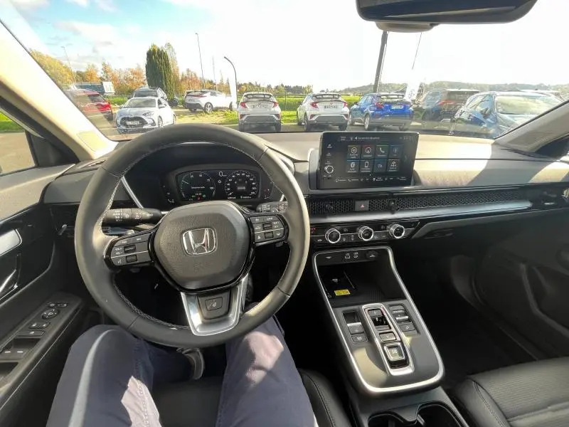 Vue intérieure du tableau de bord et volant cuir noir du Honda CR-V 2024 avec écran tactile central et commandes au volant.