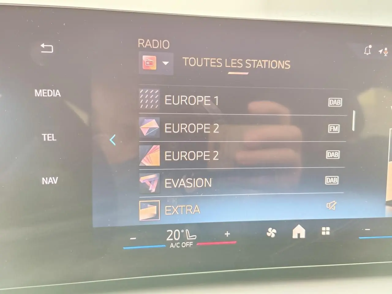 Écran tactile central de la BMW Série 1 2025 affichant les stations radio avec interface moderne et commandes climatisation.