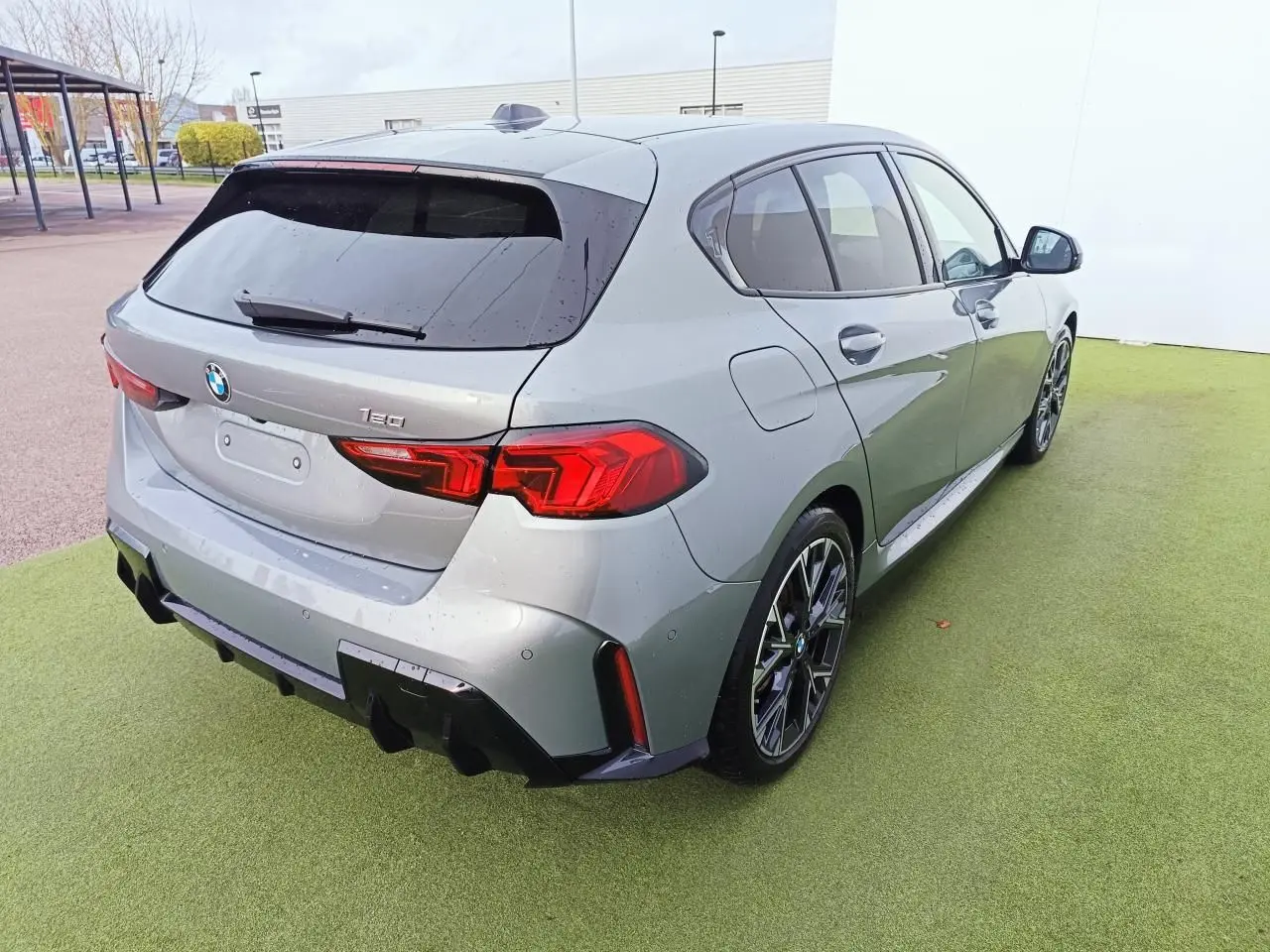 BMW Série 1 gris Skyscraper vue 3/4 arrière droit, toit noir et jantes alliage 18 pouces M Sport.