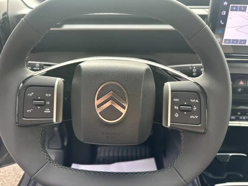 Vue rapprochée du volant noir du Citroën C3 2025 avec commandes intégrées et logo chromé central.