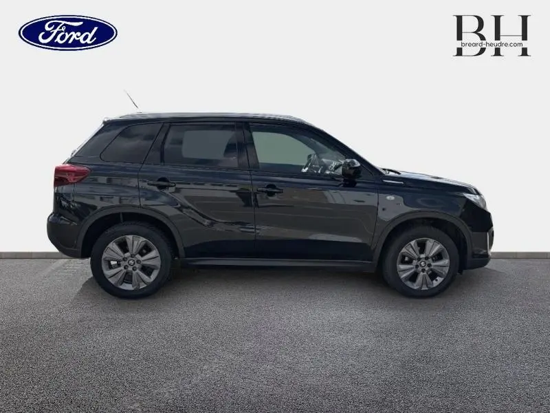 Vue de profil droit d'un Suzuki Vitara Cosmic Black Pearl métallisé, soulignant ses jantes alu et ses vitres teintées.