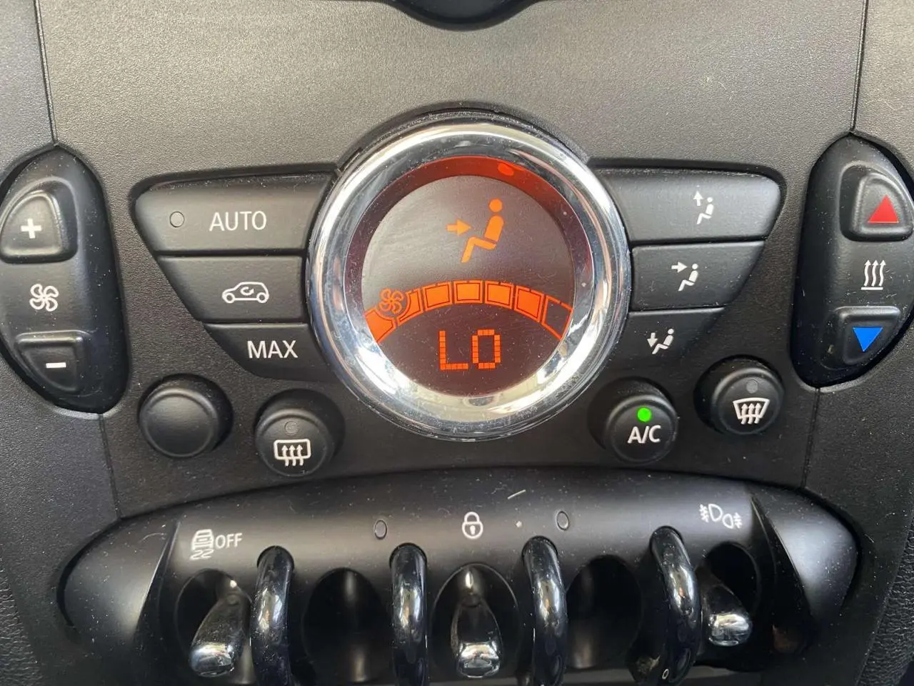 Gros plan sur les commandes de climatisation automatique avec affichage digital orange dans une MINI Countryman gris clair.