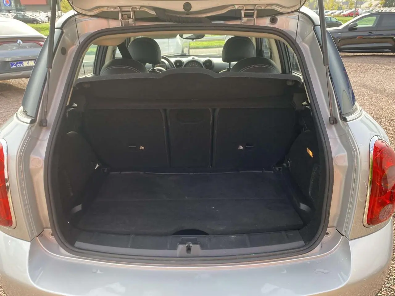 Vue arrière ouverte du coffre d'une MINI Countryman gris clair, montrant l'espace de chargement et la banquette arrière.