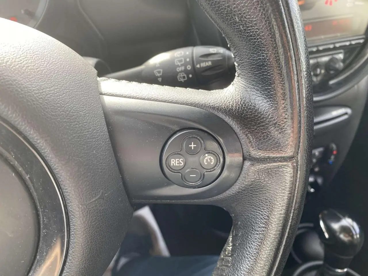 Gros plan sur le volant en cuir noir d'une MINI Countryman gris clair, avec commandes de régulateur de vitesse visibles.