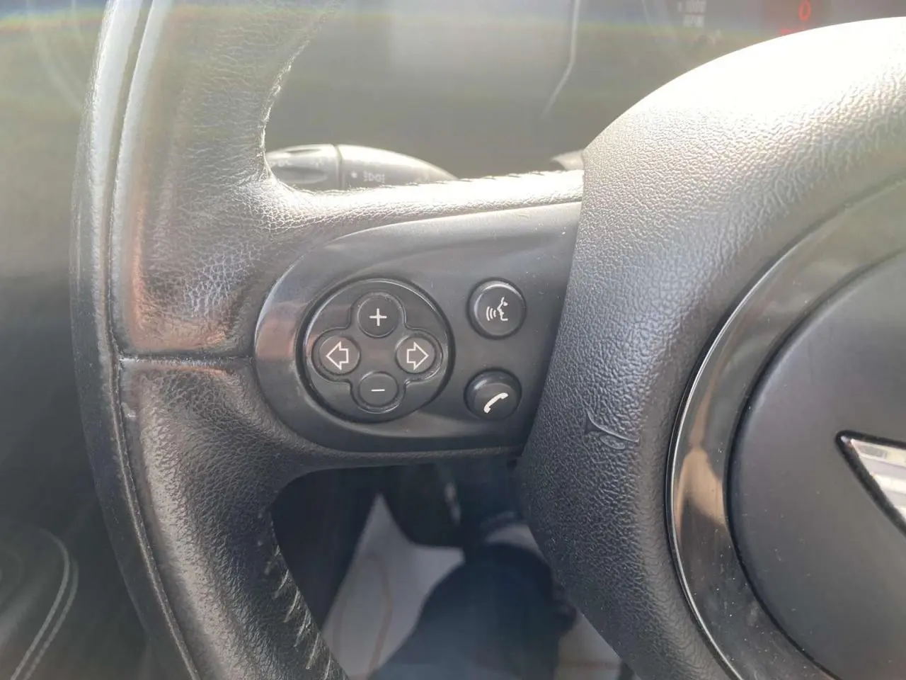 Gros plan sur les commandes du volant en cuir noir d'une MINI Countryman 2015, version Cooper D diesel.