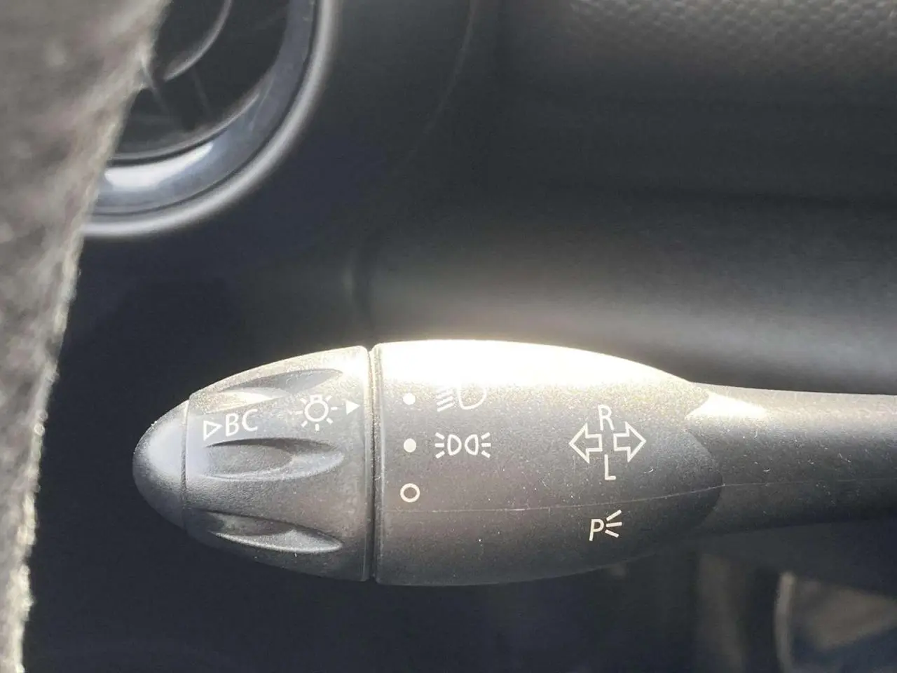 Gros plan sur la commande des clignotants et phares à gauche du volant dans l’habitacle d’un MINI Countryman gris clair.
