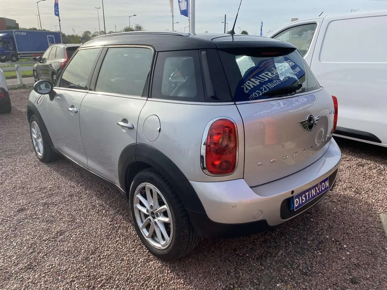 Vue 3/4 arrière droite d'une MINI Countryman gris clair avec toit noir et feux arrière ronds.