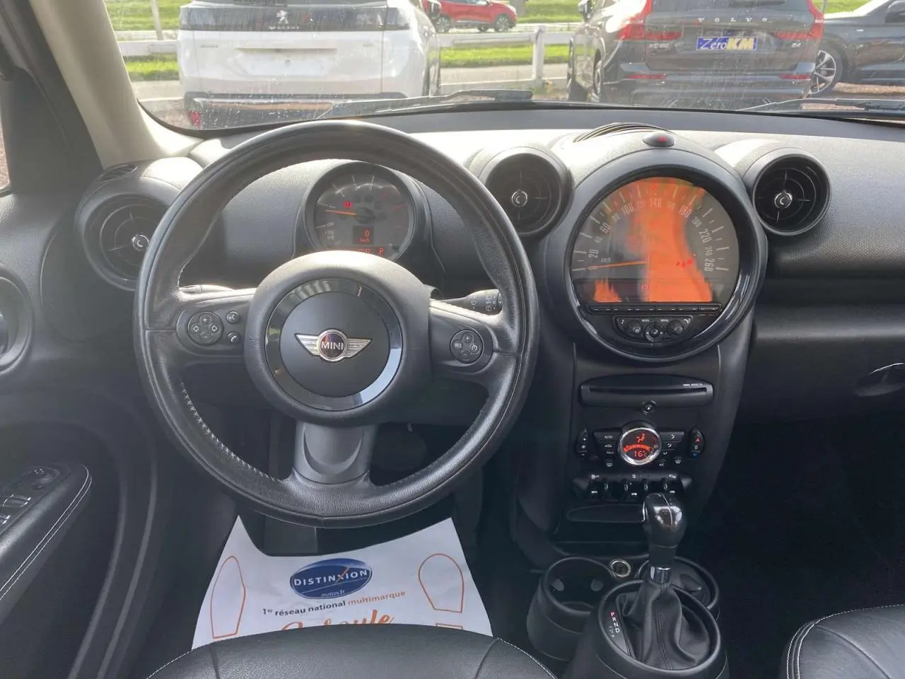 Vue intérieure frontale du tableau de bord et volant cuir noir d'une MINI Countryman gris clair de 2015 avec boîte auto.