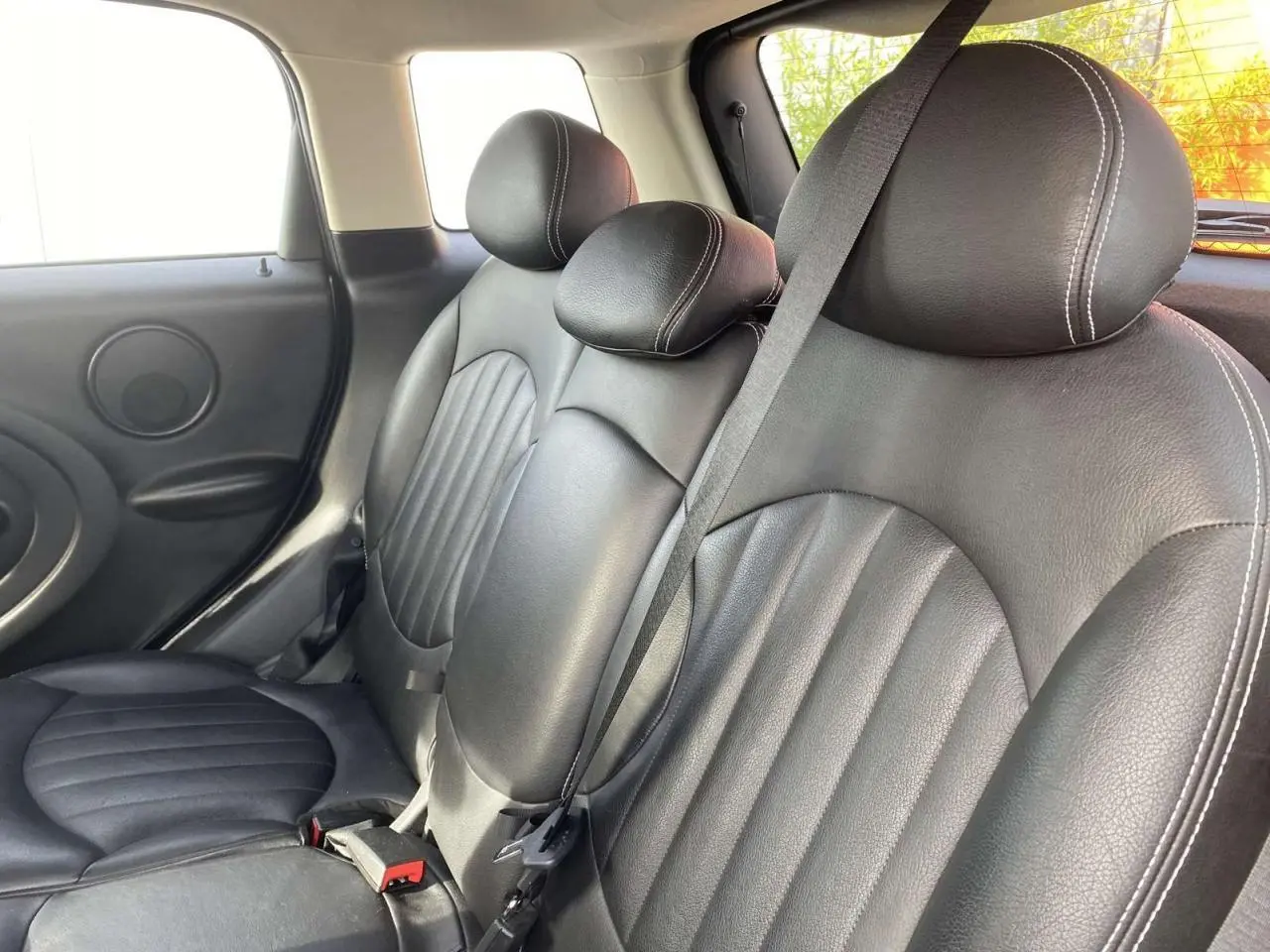 Vue intérieure des sièges arrière en cuir noir du MINI Countryman gris clair, avec ceinture de sécurité visible.