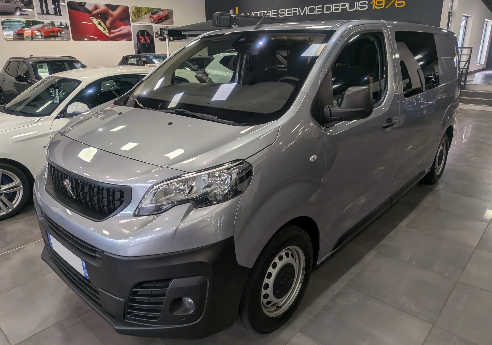 Peugeot Expert Fourgon gris acier vu en 3/4 avant droit, avec calandre noire et pare-chocs noir mat en intérieur showroom.