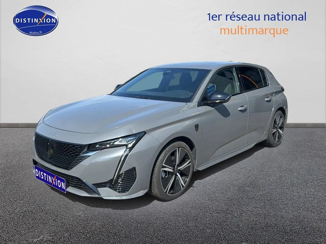 Peugeot 308 gris vue 3/4 avant droit, avec jantes alu et calandre noire distinctive.