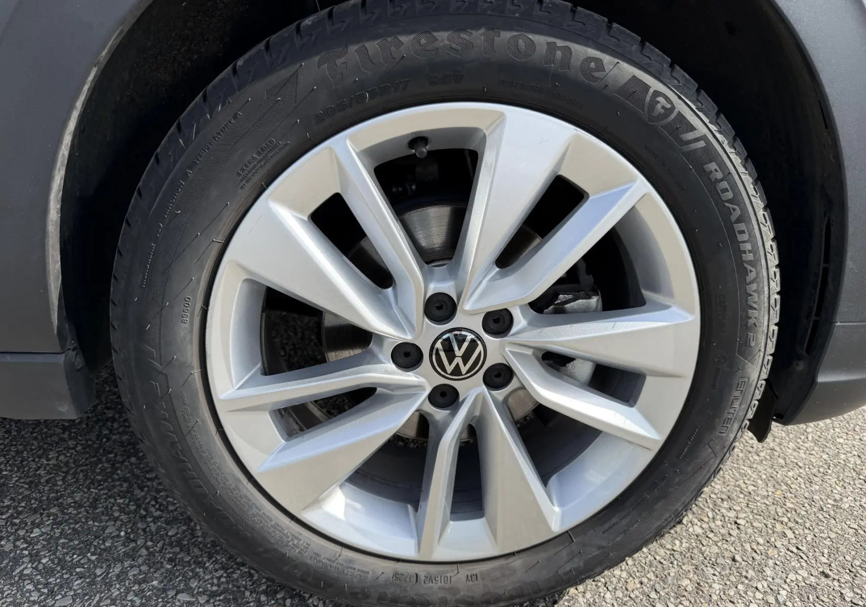 Gros plan sur la jante alliage 17 pouces argentée avec logo Volkswagen au centre du Volkswagen Taigo bleu.