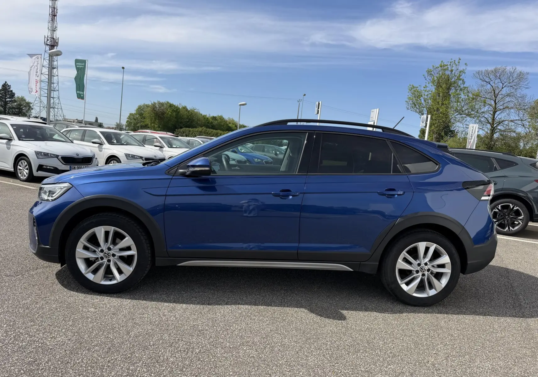 Vue de profil côté gauche d'un Volkswagen Taigo bleu métallisé avec jantes alliage 17 pouces sur un parking extérieur.