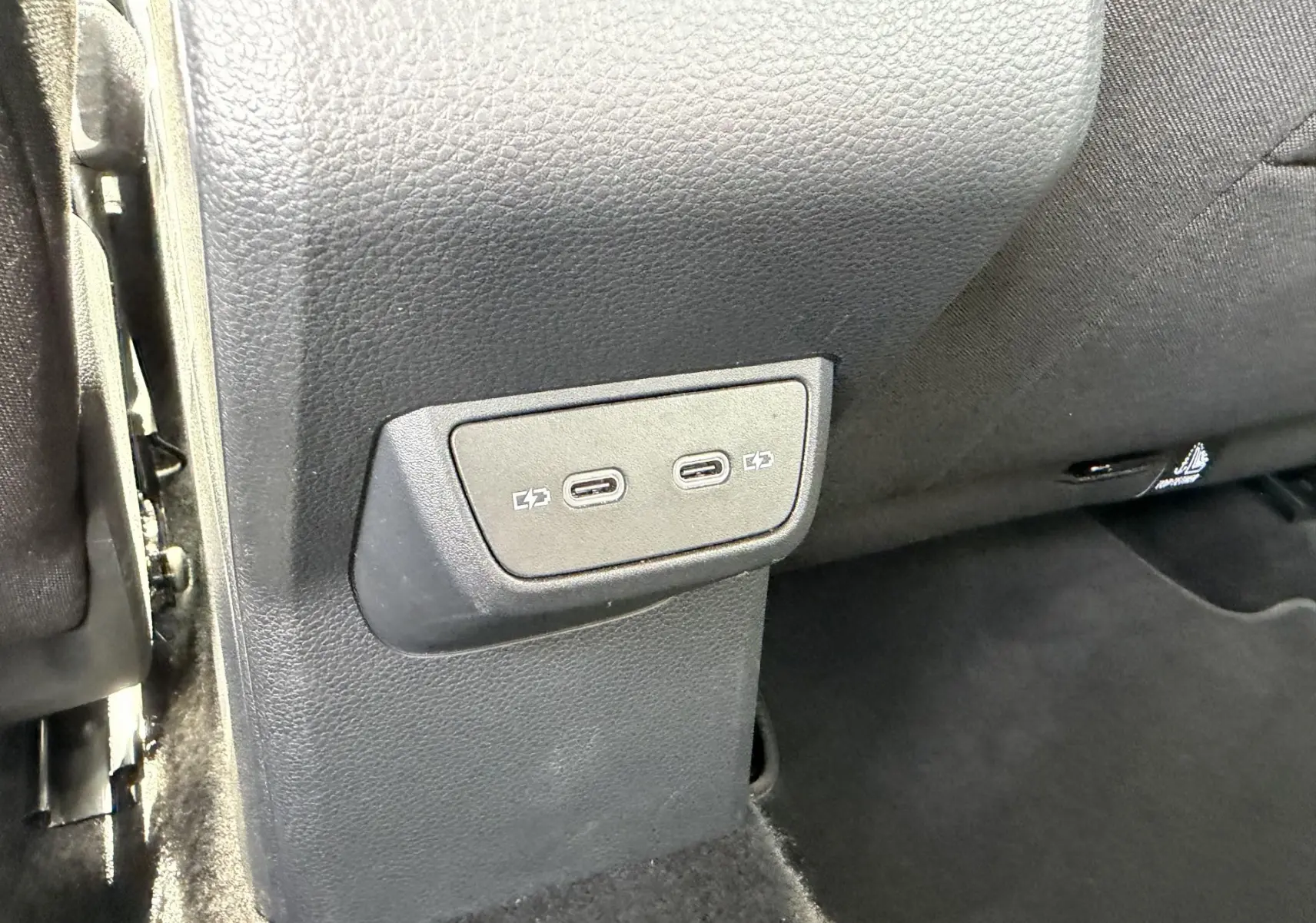 Prise USB-C double en gros plan sur la console arrière du Volkswagen Taigo, intérieur noir.