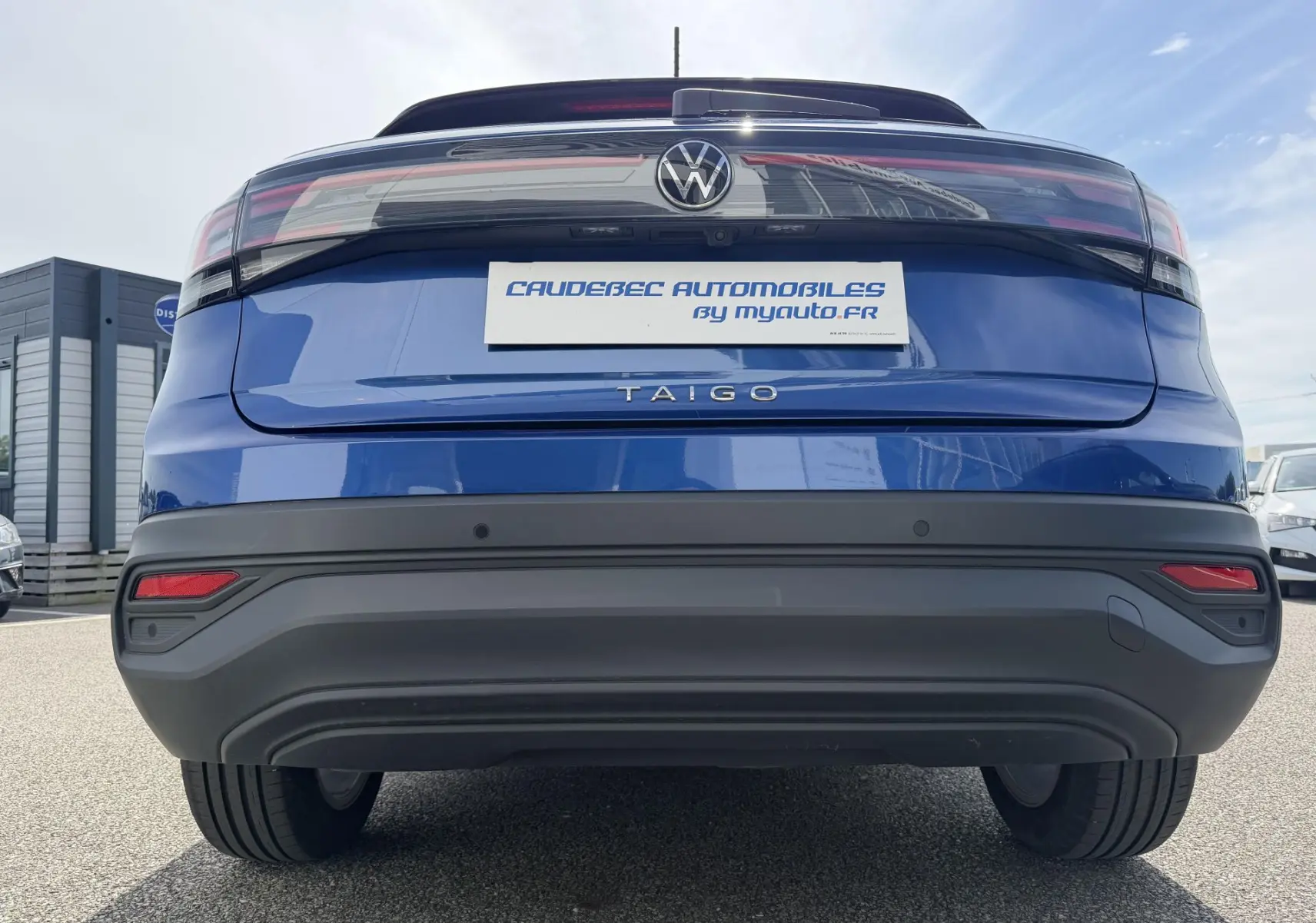 Vue arrière d'un Volkswagen Taigo bleu métallisé avec feux arrière LED et logo central visible.