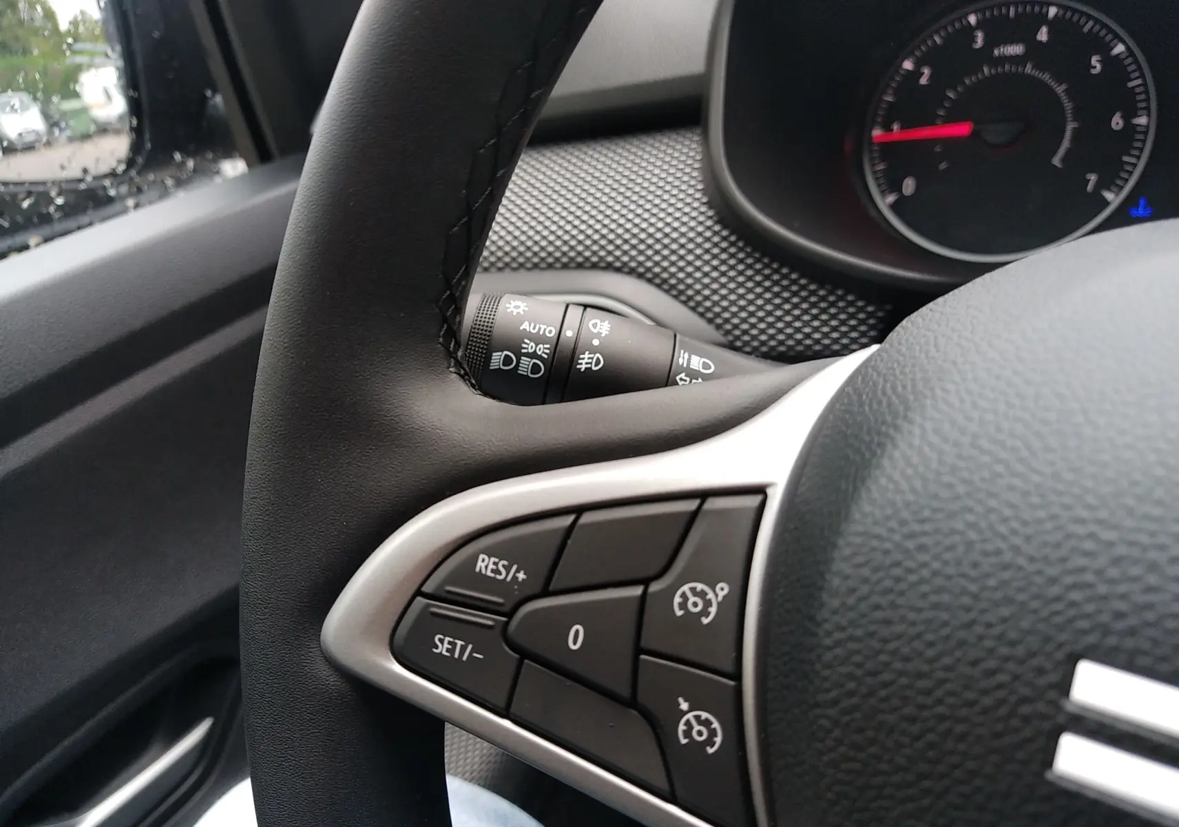 Gros plan sur le volant côté gauche de la Dacia Sandero 2025, avec commandes de régulateur de vitesse visibles.