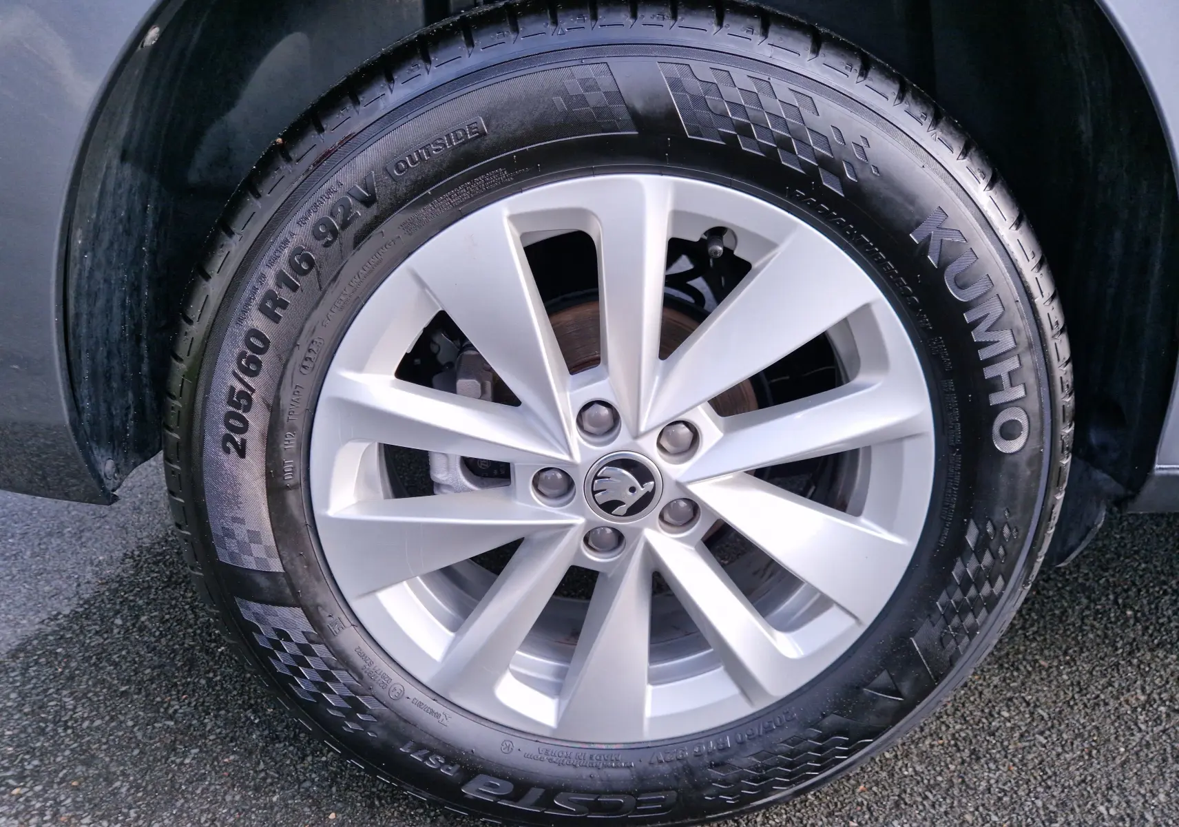 Gros plan sur la jante argentée avec logo Skoda d'un KAMIQ gris graphite, mettant en valeur le pneu Kumho 205/60 R16.