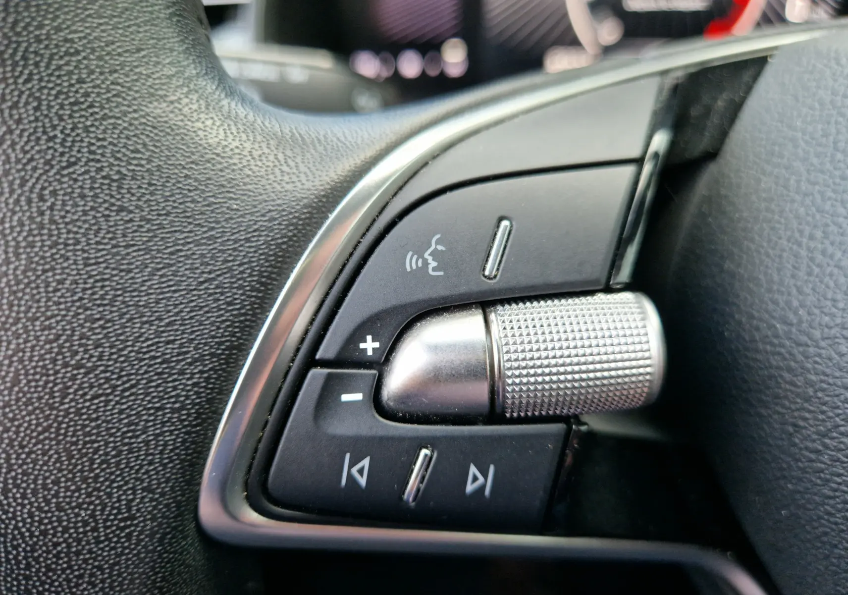 Gros plan sur les commandes argentées et noires du volant du Skoda Kamiq 2024, finition gris graphite métal.