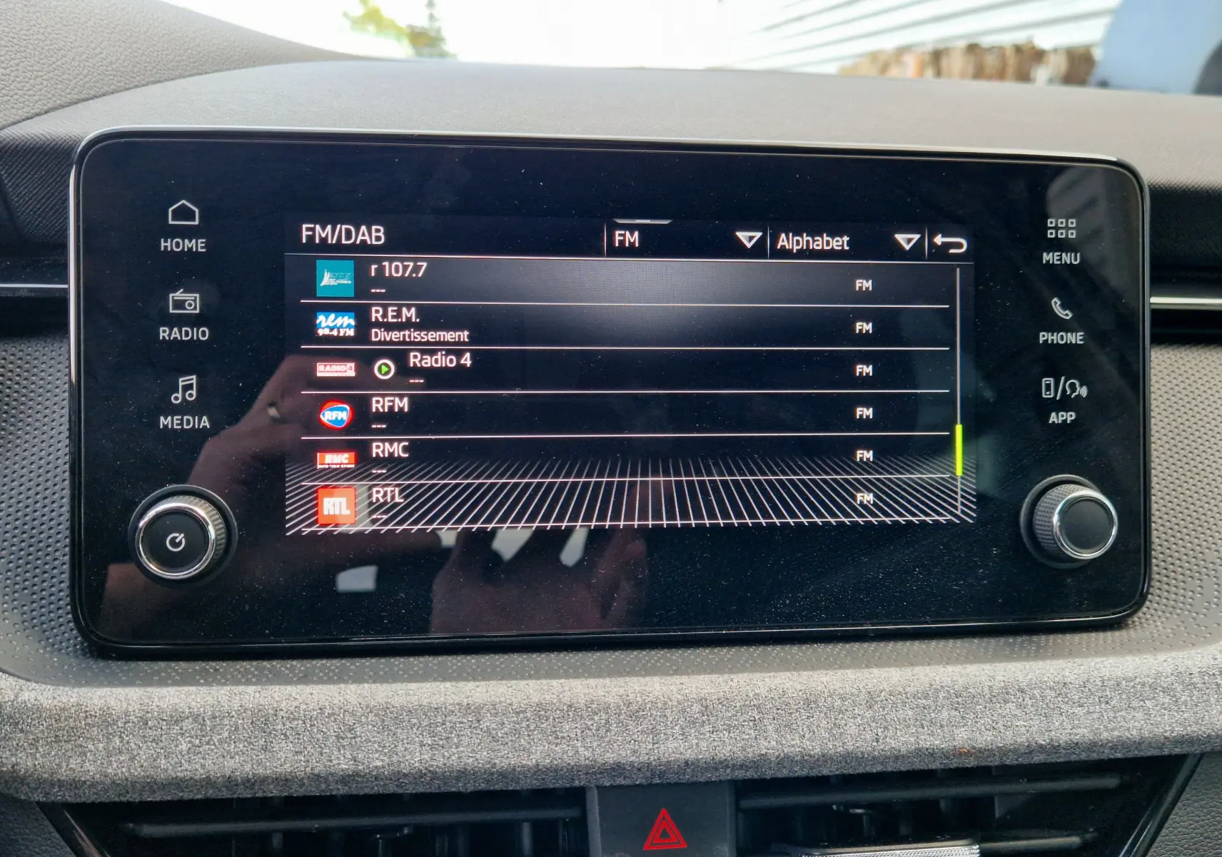 Écran tactile central du Skoda Kamiq 2024 affichant les stations radio FM avec commandes autour, intérieur gris.