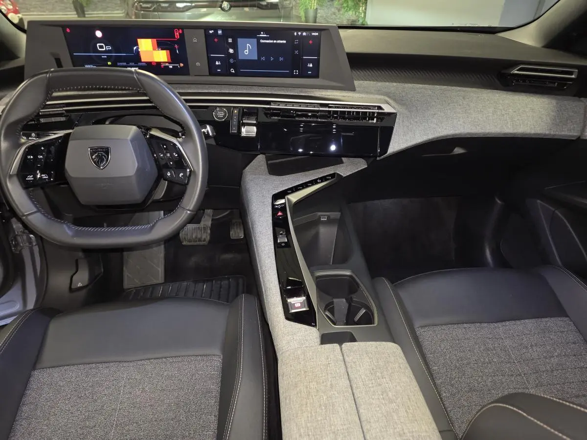 Vue intérieure avant du Peugeot 3008 gris 2025, mettant en valeur le tableau de bord tissu Rimini et double écran HD flottant.
