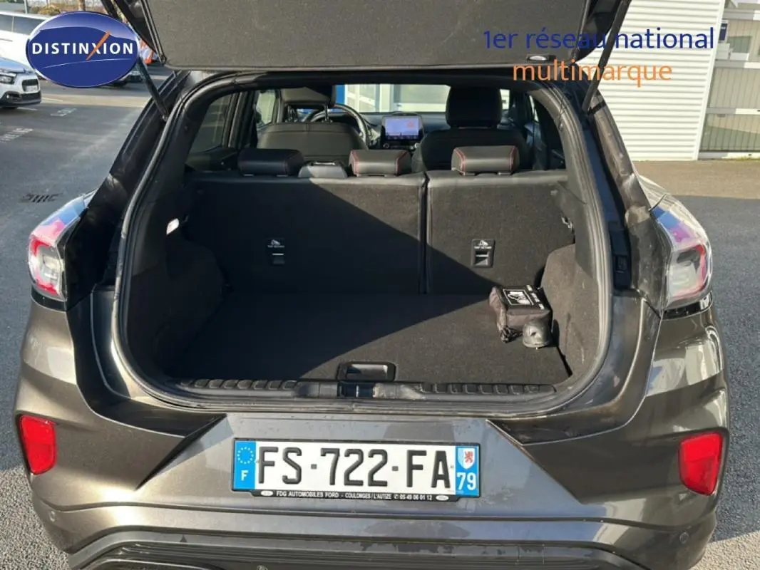 Vue arrière ouverte du coffre d’un Ford Puma gris foncé 2020, montrant l’espace de chargement et les sièges arrière.