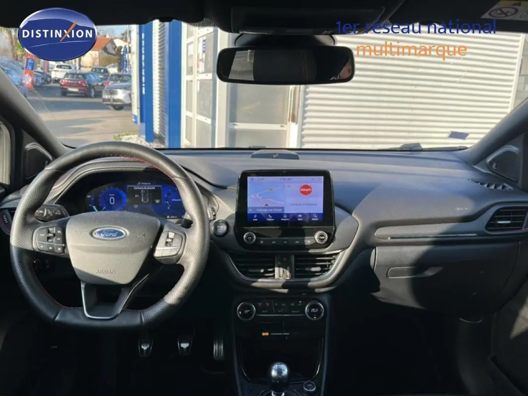 Vue intérieure avant du Ford Puma gris foncé, mettant en valeur le tableau de bord avec écran tactile et volant multifonction.
