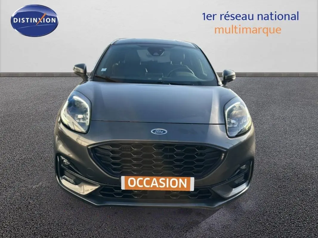 Vue avant d'une Ford Puma gris foncé avec calandre noire et feux allumés sur fond neutre.