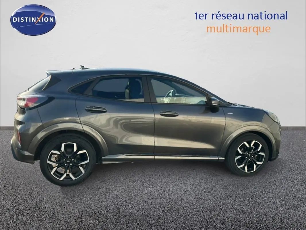 Vue de profil côté gauche d'un Ford Puma gris foncé avec jantes alliage 18 pouces et vitres surteintées.