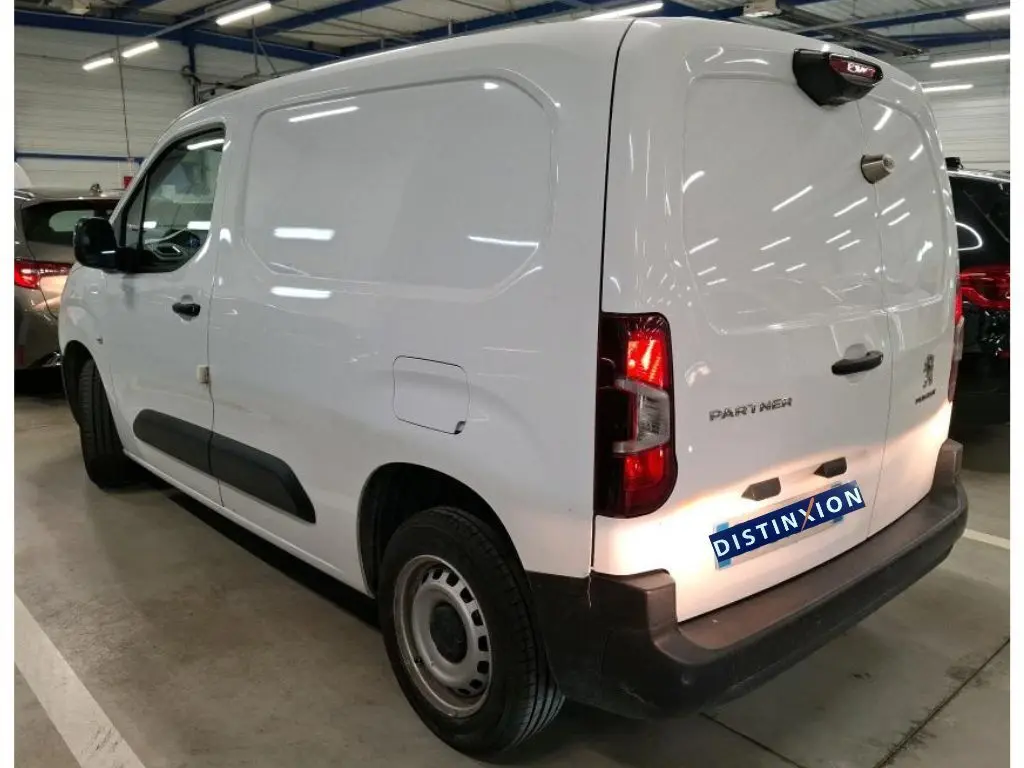 Vue 3/4 arrière droite d’un Peugeot Partner Fourgon blanc 2022 avec portes arrière fermées et protections noires.