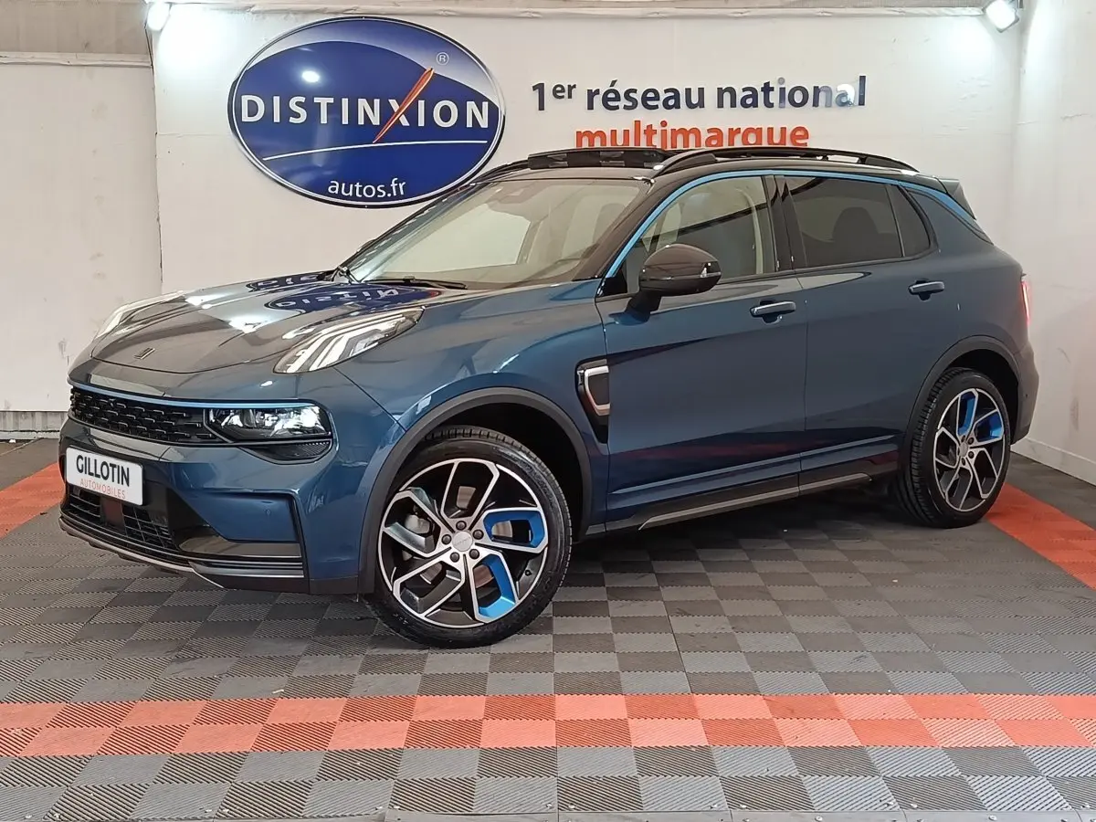 Vue 3/4 avant droit d'un SUV Link & Co 01 bleu avec jantes bicolores et toit ouvrant en intérieur showroom.