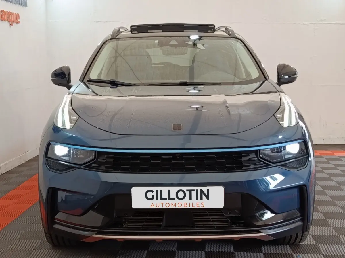 Vue frontale d'un SUV Link & Co 01 hybride rechargeable bleu avec phares LED allumés et calandre noire.