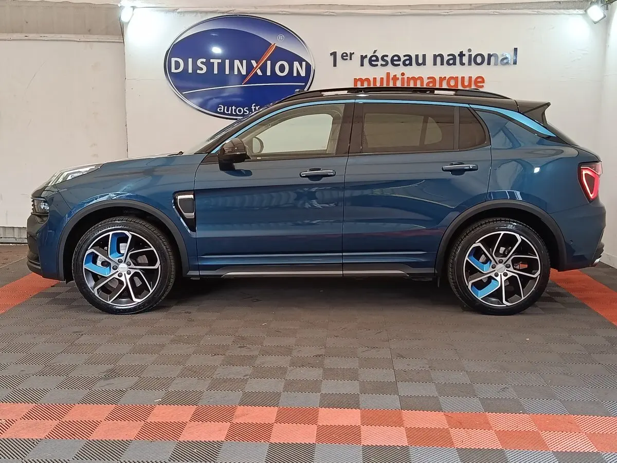 Vue de profil côté gauche d'un SUV Link & Co 01 hybride rechargeable bleu avec jantes noires et bleues, toit noir et feux arrière triangulaires.