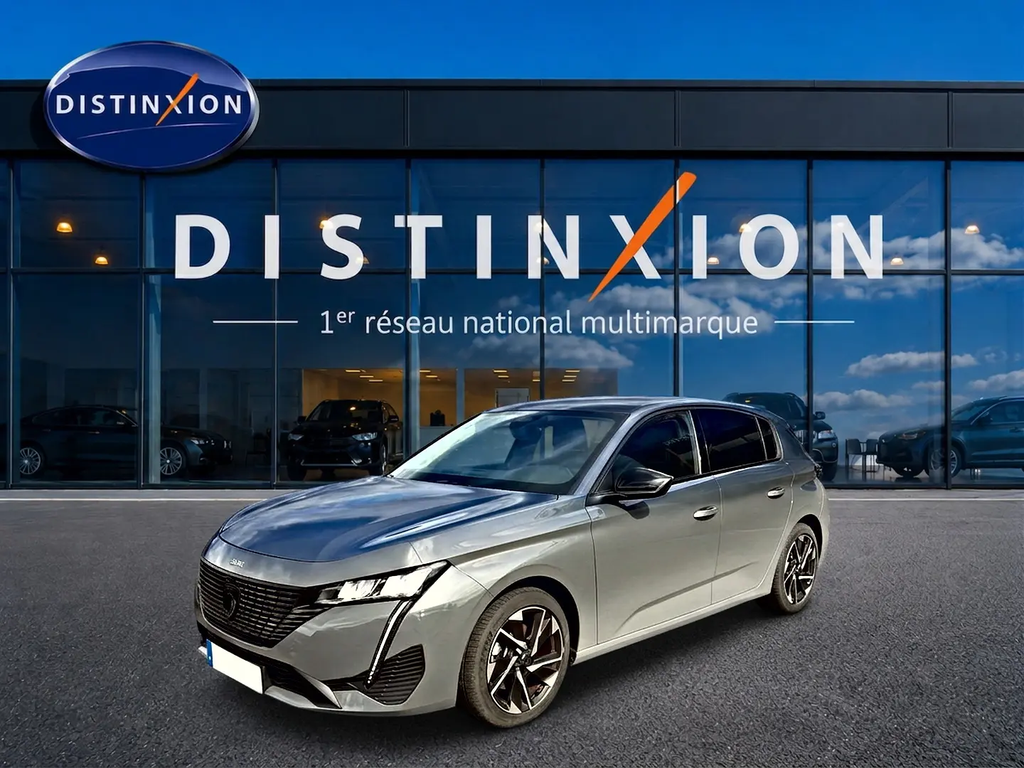 Peugeot 308 gris selenium vue 3/4 avant droit devant une vitrine Distinxion avec jantes alu noires.