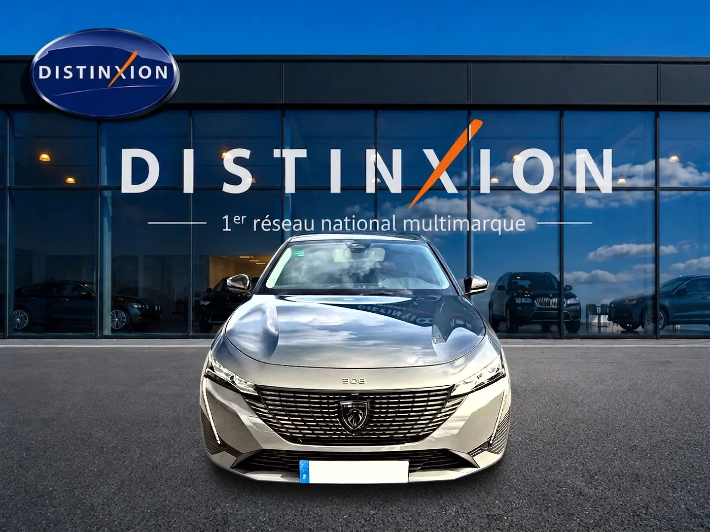 Vue avant d'une Peugeot 308 gris selenium garée devant une vitrine avec logo Distinxion.