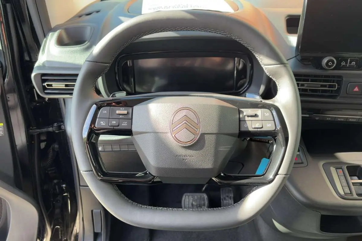 Vue rapprochée du volant cuir multifonctions gris du Citroën Berlingo Noir Perla Nera 2026 avec tableau de bord numérique.