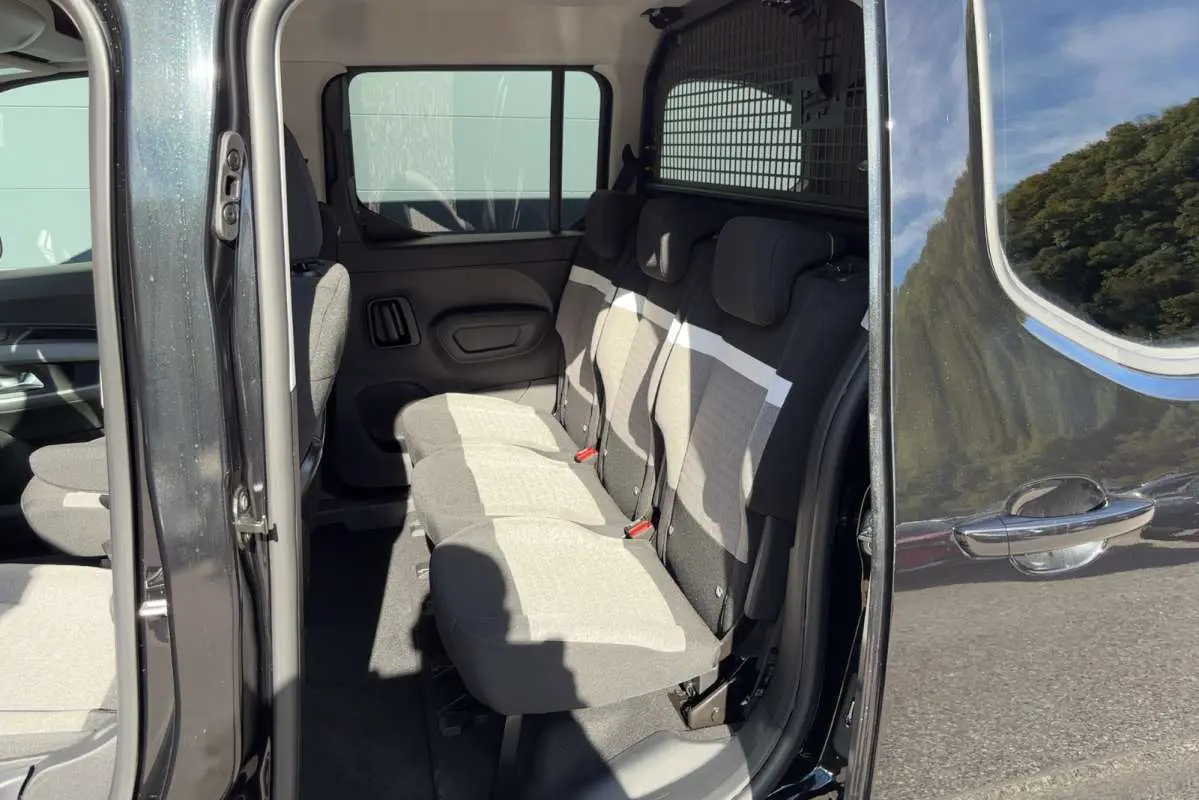 Vue latérale droite ouverte sur l'intérieur du Citroën Berlingo noir perla nera, montrant les trois sièges arrière indépendants en tissu gris.