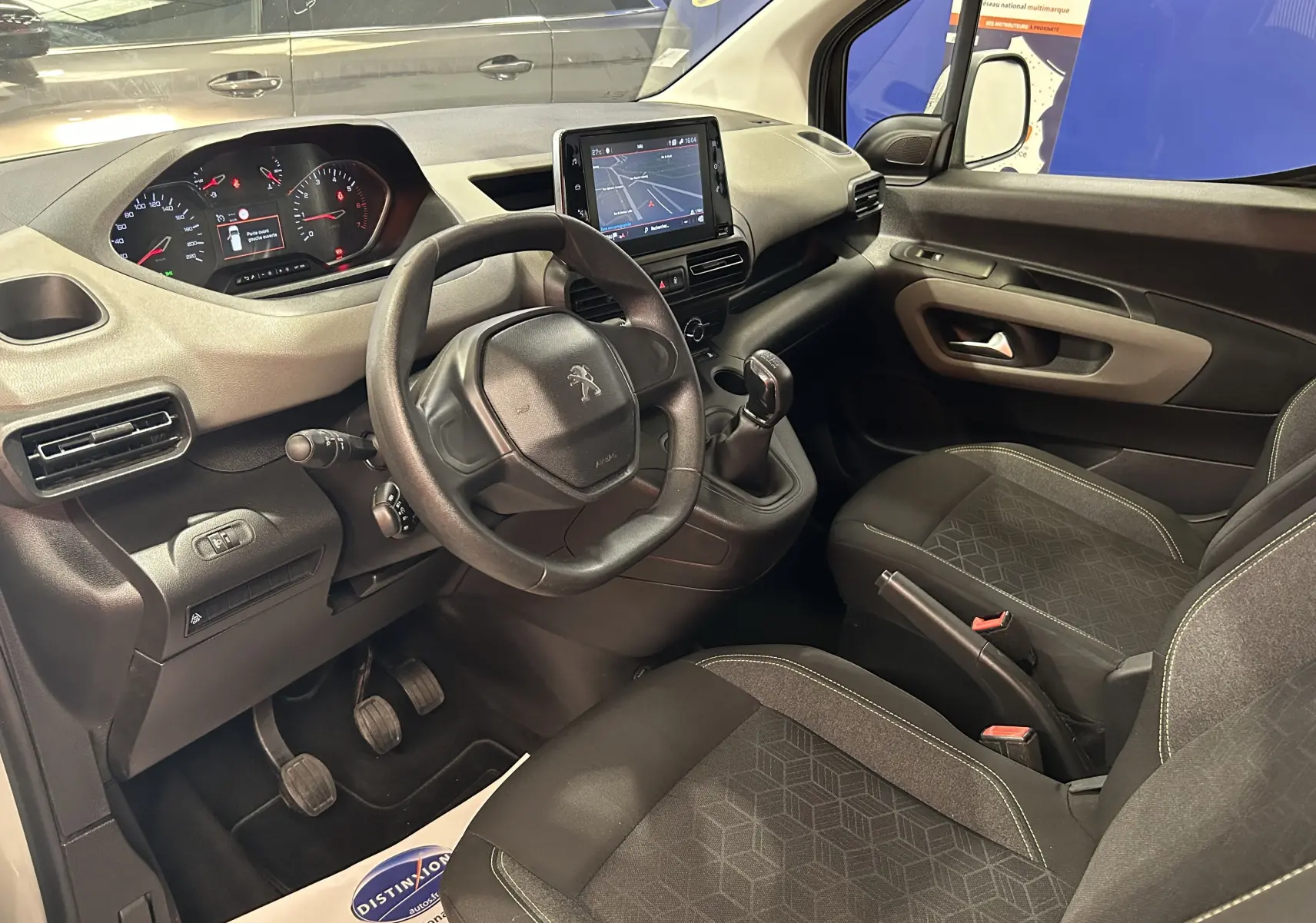Intérieur du Peugeot Rifter gris sable 2019, vue côté conducteur, tableau de bord avec GPS et boîte manuelle visible.