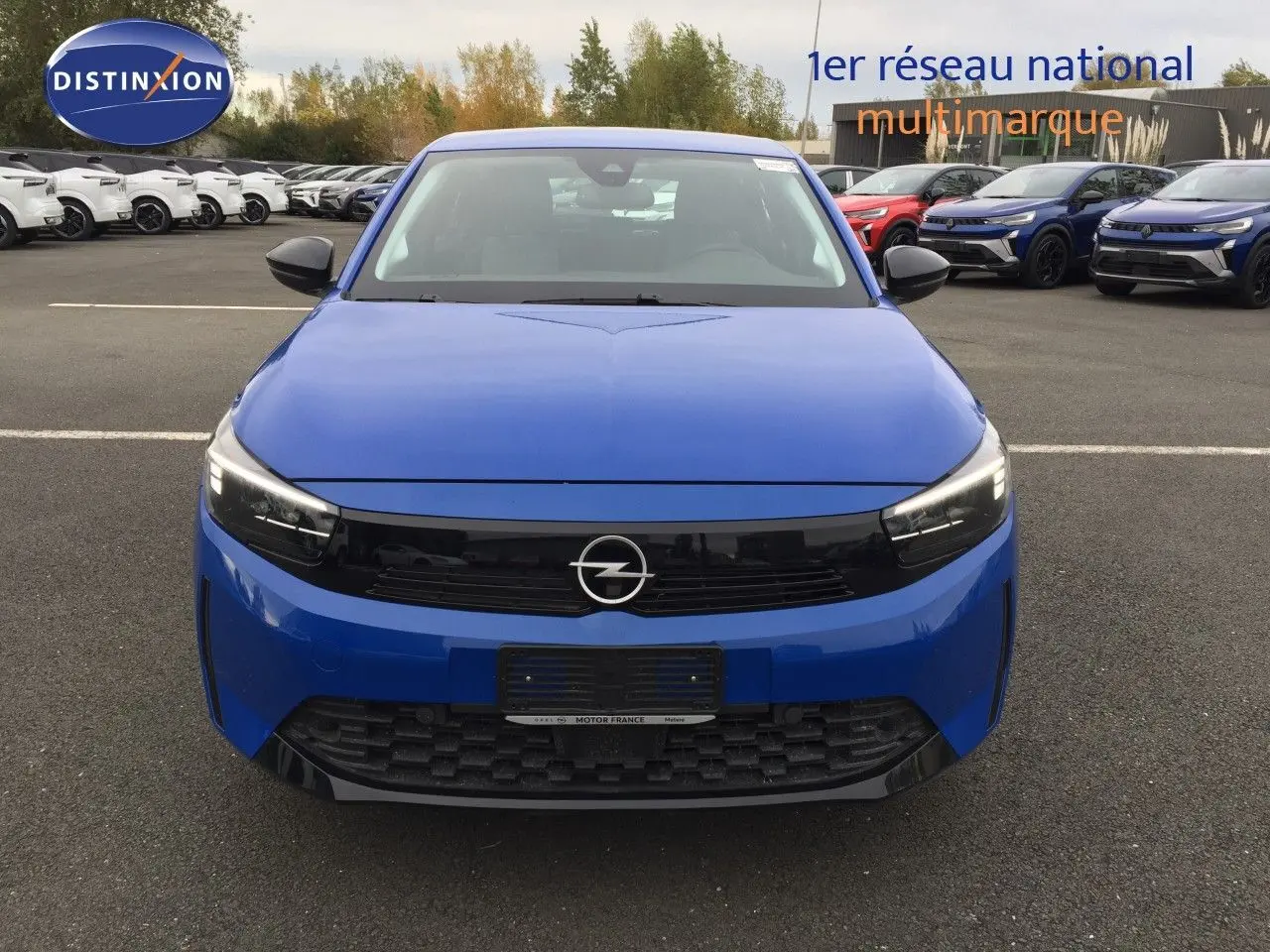 Opel Corsa 2025 bleu voltaik metal vue de face, avec calandre noire et phares LED allumés.