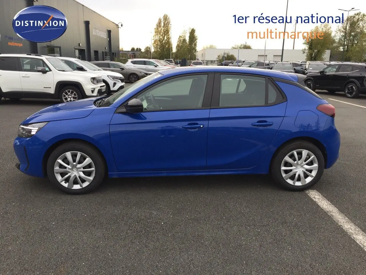 Profil côté gauche d'une Opel Corsa 2025 bleu voltaik métal, compacte à cinq portes sur un parking extérieur.