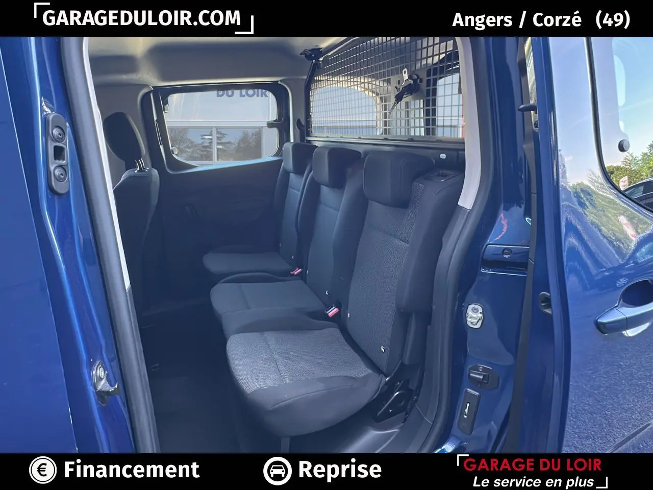 Vue intérieure côté droit sur la banquette arrière noire du Peugeot Rifter bleu avec cloison de séparation métallique.