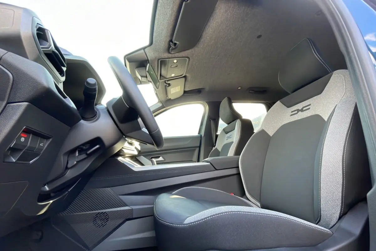 Intérieur du Dacia Bigster Hybrid 155 Journey City, vue côté conducteur sur les sièges bi-matière avec logo DC brodé.