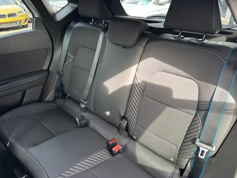 Vue intérieure arrière du Renault Captur 2026, sièges noirs avec surpiqûres bleues et ceinture assortie côté droit.